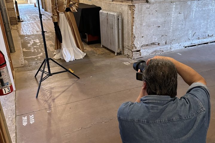 Photographer capturing a model in a rustic indoor setting with studio lights.