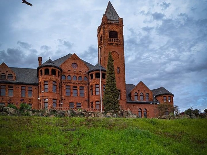 a large brick building with a tower in the middle of a field