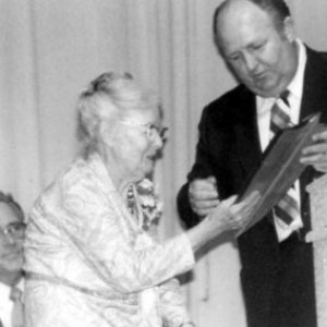 a group of people standing next to a man in a suit and tie
