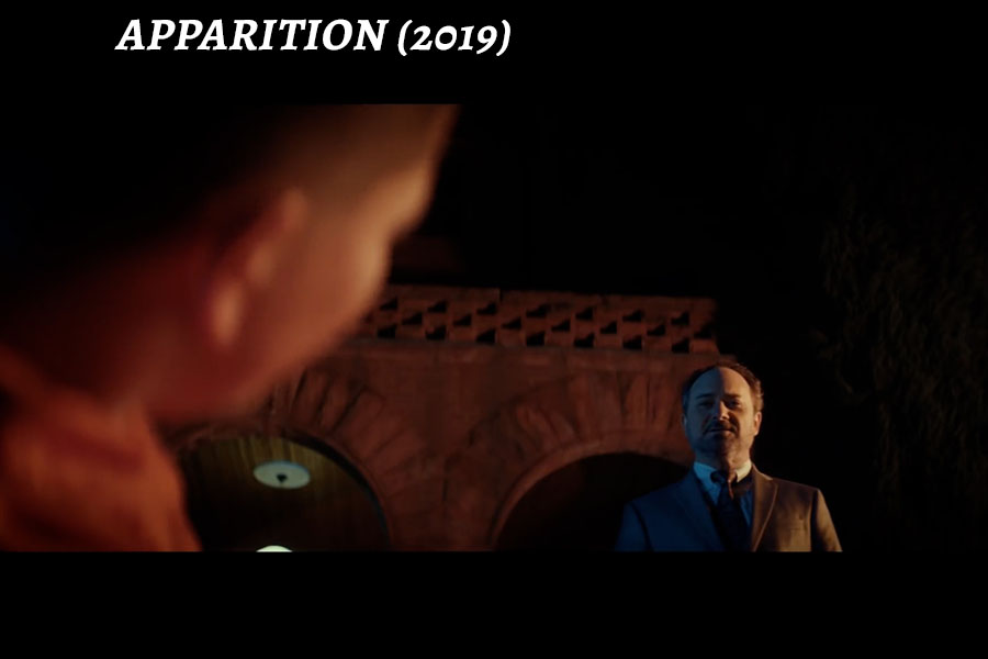 a screen shot of Kevin Pollak in a dark room