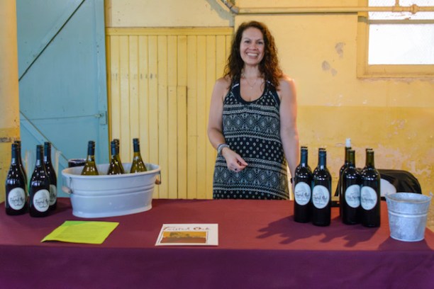 a person standing next to a bottle of wine on a table
