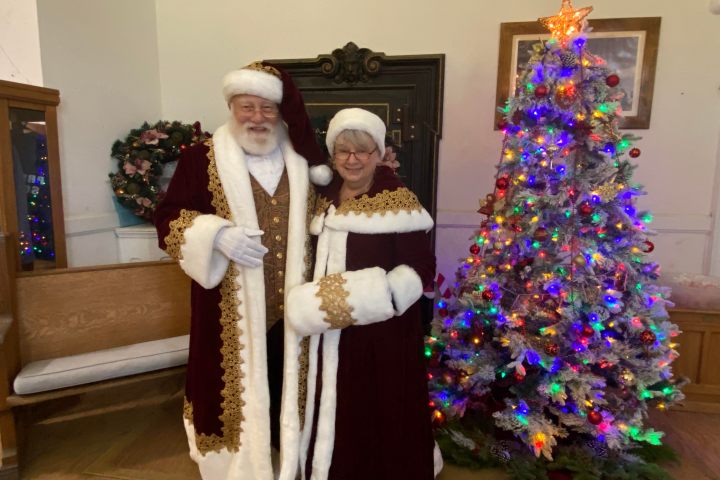 a woman standing next to a christmas tree
