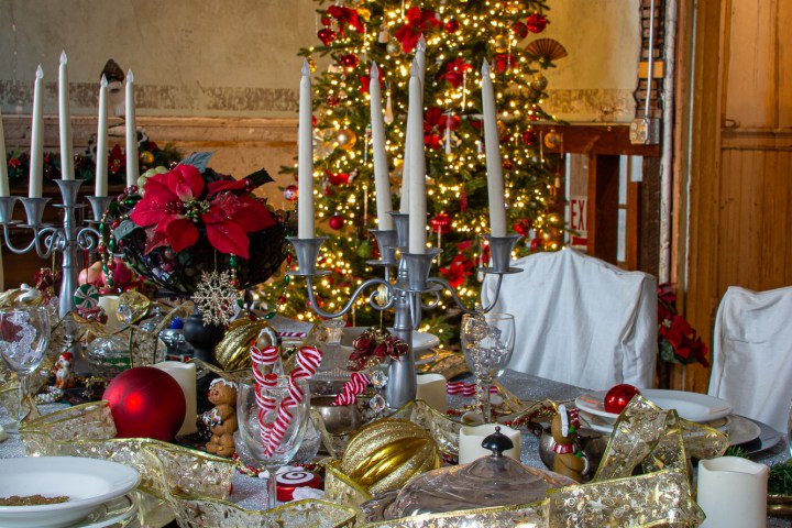 Festive table setting with candles and decorations in front of a lit Christmas tree.