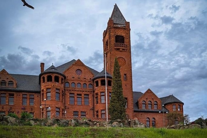 a large brick building with grass in front of a church