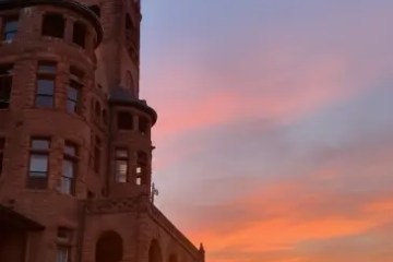 Historic building with turret at sunset, sky filled with vibrant orange and blue hues.