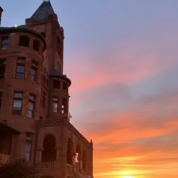 Historic building with turret at sunset, sky filled with vibrant orange and blue hues.