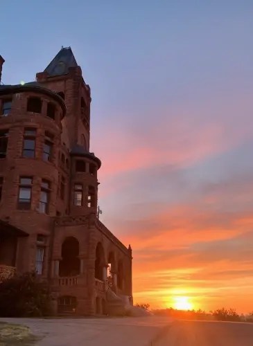 Historic building with turret at sunset, sky filled with vibrant orange and blue hues.